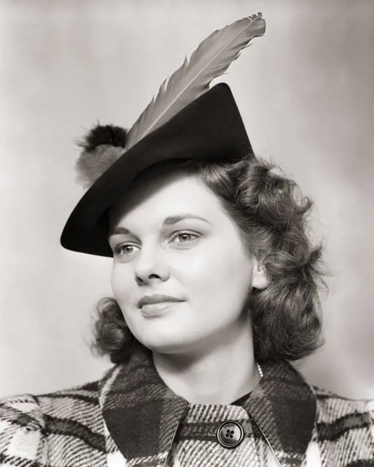 1930s 1940s PORTRAIT SMILING YOUNG WOMAN TEEN WEARING WOOLEN PLAID COAT AND JAUNTY HAT WITH LARGE FEATHER