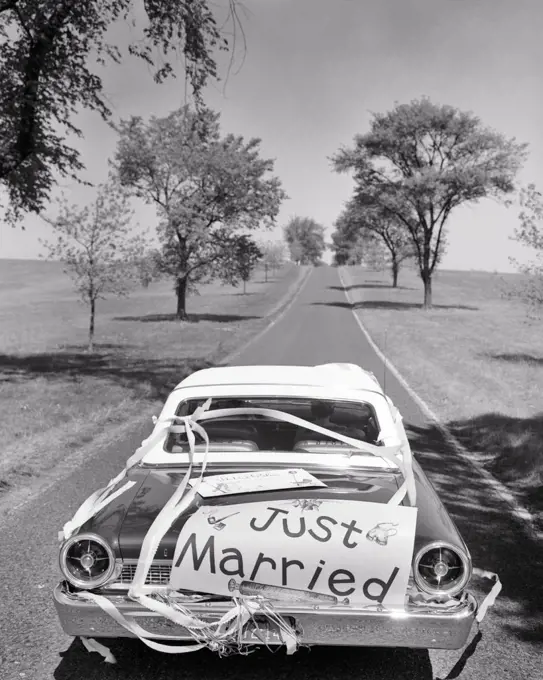 1960s ANONYMOUS NEWLYWED COUPLE IN CONVERTIBLE CAR WITH JUST MARRIED SIGN ON BACK DRIVING ON UP HIGHWAY OFF INTO THE FUTURE