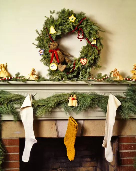 1980s CHRISTMAS FIREPLACE MANTLE DECORATED WITH HOMESPUN HAND CRAFTED ITEMS WREATH GARLAND STOCKINGS ORNAMENTS