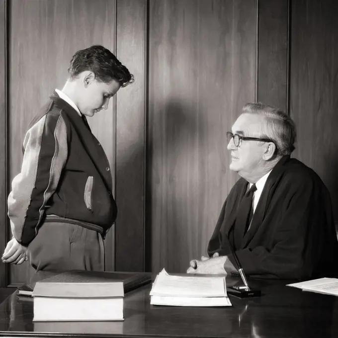 1940s 1950s TEENAGE BOY HEAD LOWERED IN SHAME TALKING TO JUDGE A SENIOR MAN