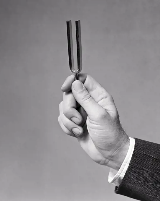 1940s MALE HAND HOLDING A TUNING FORK