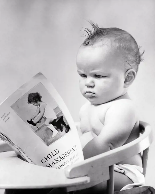 1940s FROWNING FLUMMOXED DISAPPROVING GRUMPY BABY BOY SITTING IN CHAIR READING A PUBLICATION TITLED CHILD MANAGEMENT