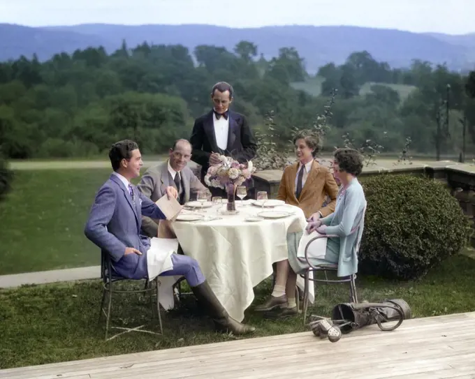 1920s 1930s COUNTRY CLUB SCENE WITH TWO COUPLES WITH GOLF CLUBS HAVING LUNCH OUTDOORS