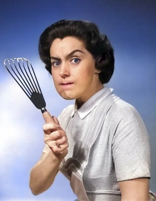 1950s 1960s PORTRAIT OF ANGRY WOMAN HOUSEWIFE LOOKING AT CAMERA BRANDISHING FOOD TURNER KITCHEN SPATULA