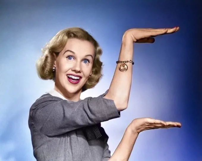 1950s 1960s HAPPY SMILING BLOND WOMAN LOOKING AT CAMERA GESTURING WITH HANDS SHOWING DESCRIBING SIZE OF SOMETHING