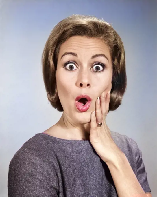 1960s PORTRAIT WOMAN WITH HAND ON CHEEK LOOKING AT CAMERA WITH SHOCKED SURPRISED ALARMED EXPRESSION
