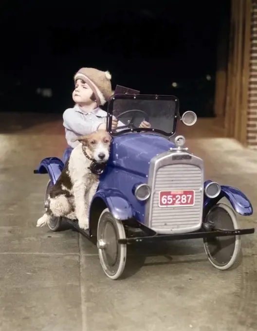1920s GIRL IN TOY PEDAL CAR WITH DOG SITTING ON RUNNING BOARD GIRL LOOKING TO SIDE HEAD UP