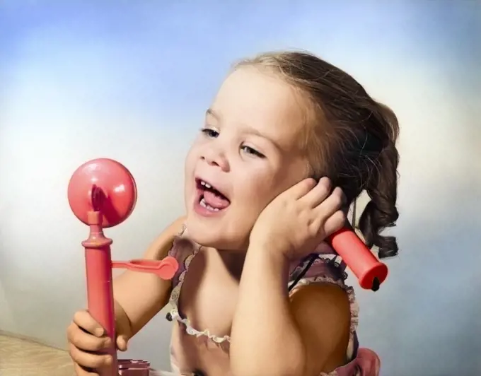 1950s HAPPY LITTLE GIRL TALKING INTO TOY TELEPHONE