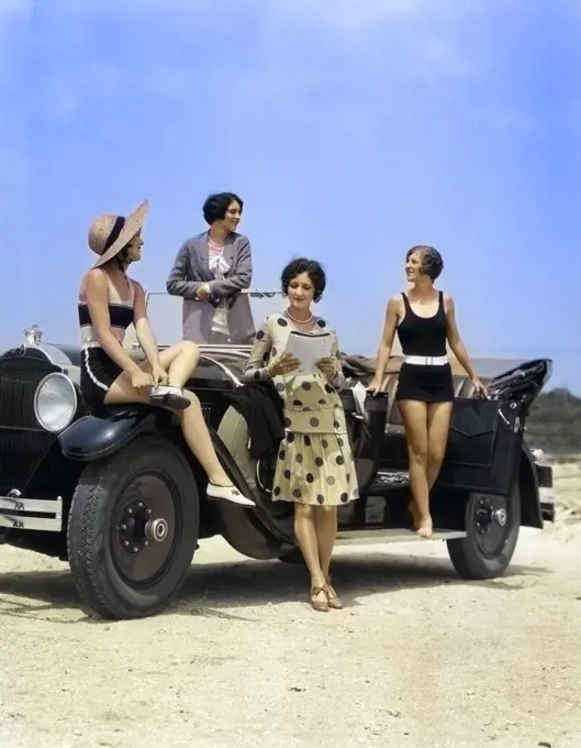 1920s 1930s FOUR WOMEN IN DRESSES AND BATHING SUITS GATHERED AROUND CONVERTIBLE TOURING CAR AT SEASHORE BEACH