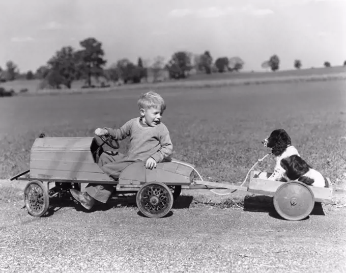 1930S 1940S Boy In Wooden Toy Car Pulling Dog Behind In Wagon