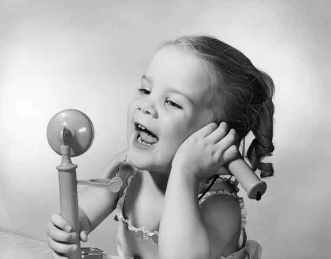 1950s HAPPY LITTLE GIRL TALKING INTO TOY TELEPHONE