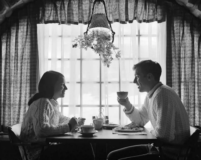 1970s SILHOUETTED COUPLE EATING BREAKFAST AT TABLE BY WINDOW