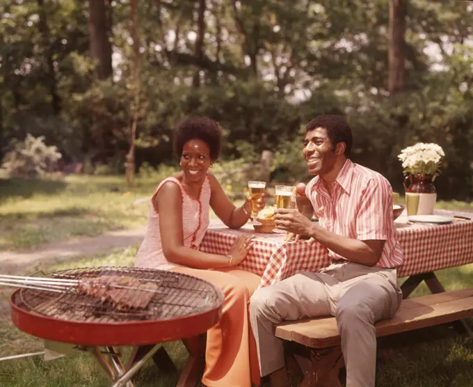 1970s SMILING AFRICAN AMERICAN COUPLE MAN WOMAN DRINKING BEER AT BACKYARD BARBECUE