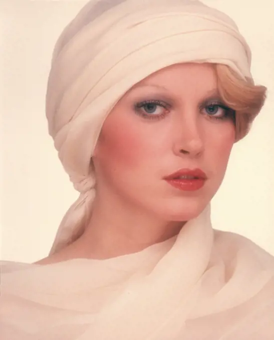 1970s PORTRAIT PRETTY BLOND WOMAN WHITE TURBAN STYLE HAT LOOKING AT CAMERA