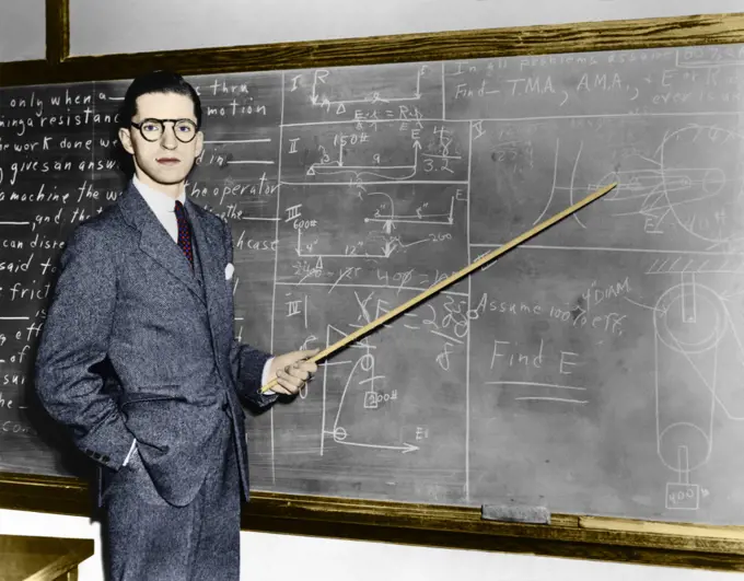  1930s 1940s MAN TEACHER PROFESSOR POINTING POINTER AT BLACKBOARD LOOKING AT CAMERA
