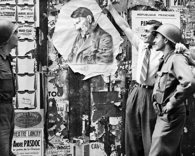 1940s CIVILIAN MAN SYMBOLICALLY HANGING ADOLF HITLER AS TWO YANK SOLDIERS LOOK ON AUGUST 26 1944 IN LATIN QUARTER PARIS FRANCE