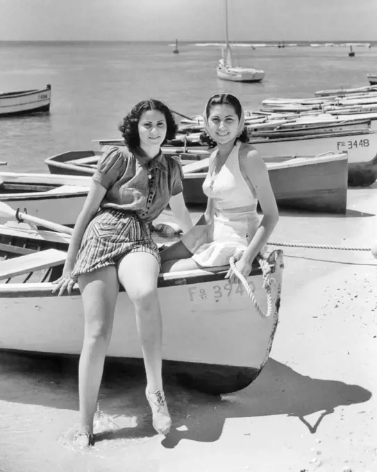 1930s 1940s TWO SMILING WOMEN SITTING ON BOW OF ROWBOAT WEARING BEACH CLOTHES LOOKING AT CAMERA LA PLAYA HAVANA CUBA