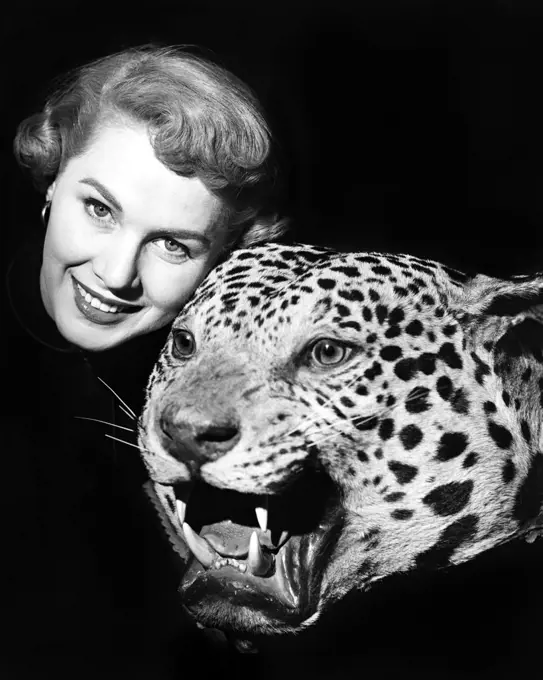 1950s SMILING WOMAN FACE LOOKING AT CAMERA POSED WITH GROWLING STUFFED LEOPARD HEAD