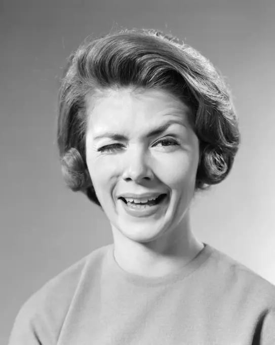 1960s BRUNETTE WOMAN WITH WACKY FUNNY FACIAL EXPRESSION WINKING ONE EYE LOOKING AT CAMERA