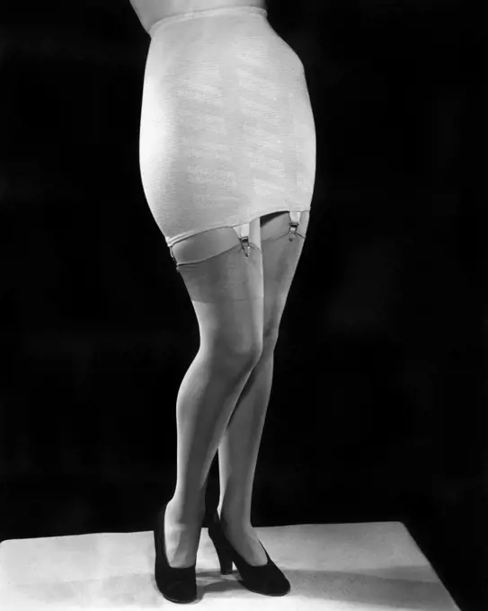 1940s FASHION WOMAN FROM WAIST DOWN WEARING GIRDLE WITH GARTERS CLIPS HOLDING SILK NYLON HOSE STOCKINGS