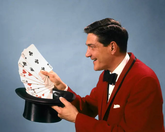 1960s 1970s MAN MAGICIAN RED SUIT BOW TIE PULLING OVERSIZE PLAYING CARDS OUT OF TOP HAT