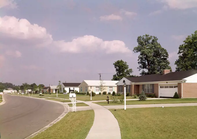 1970s SUBURBAN COMMUNITY RANCH STYLE HOUSES ALONG SIDEWALK AND STREET WITH MAILBOXES 