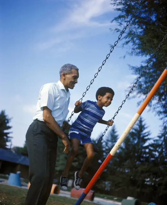 1970s AFRICAN AMERICAN MAN AND BOY SWING SET PLAYING