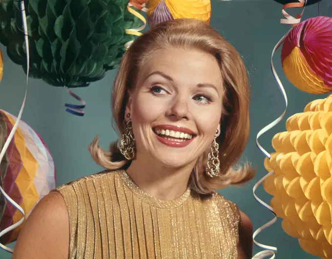 1960s SMILING BLONDE WOMAN WEARING EVENING CLOTHES GOLD LAME BLOUSE AMONG PARTY BALLOONS AND STREAMERS