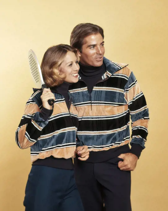 1970s SMILING COUPLE MAN WOMAN HOLDING SQUASH RACKET WEARING MATCHING STRIPED VELOUR PULLOVER SWEATERS FASHION SPORTSWEAR