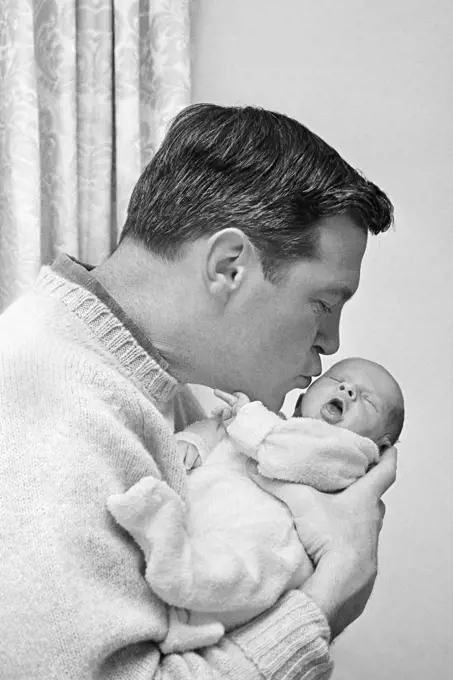 1960s FATHER HOLDING AND KISSING HIS INFANT BABY SON