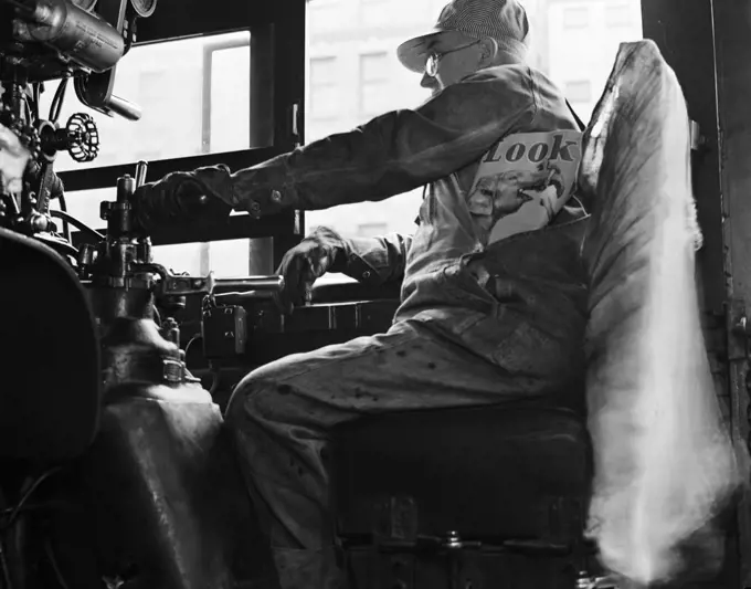 1940s ABOARD THE HIAWATHA RAILROAD TRAIN ENGINEER IN CAB OF LOCOMOTIVE WITH HAND ON THROTTLE COPY LOOK MAGAZINE IN POCKET