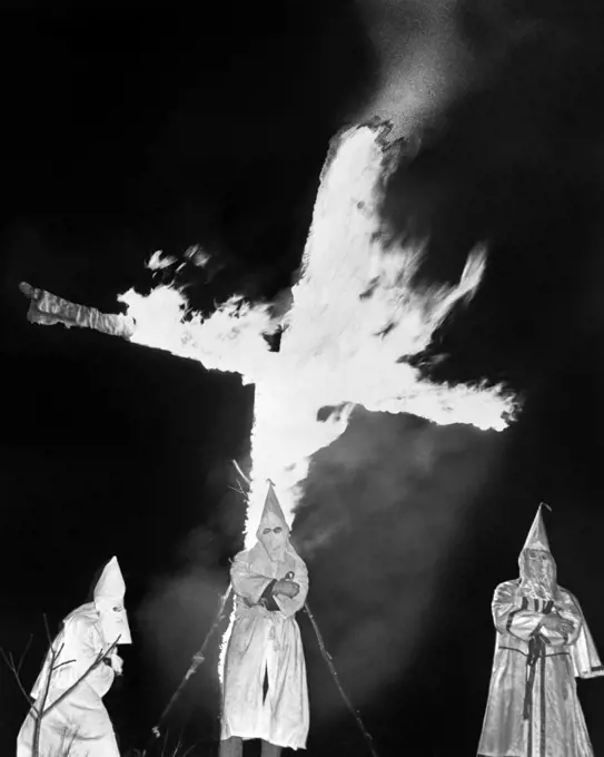 1930s HOODED MEMBERS OF KKK KU KLUX KLAN STANDING IN FRONT OF BURNING CROSS