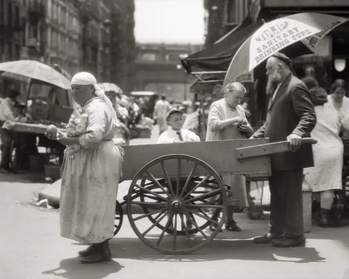 1930s DEPRESSION ERA LOWER EAST SIDE PUSHCART SCENE WITH EASTERN EUROPEAN IMMIGRANT VENDORS AND CUSTOMERS NEW YORK CITY USA
