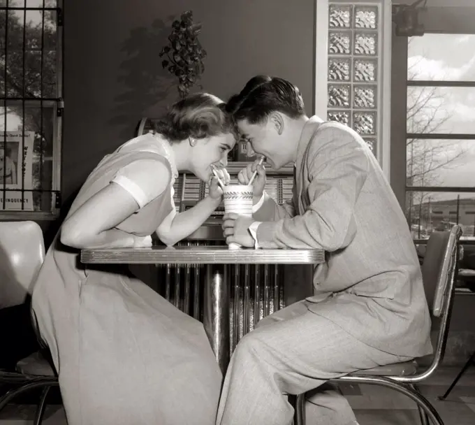 1950S 1960S Laughing Teenage Couple Boy And Girl Sharing Drink Together With Two Straws In Soda Shop