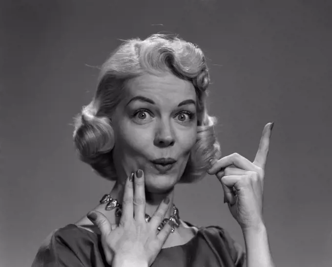 1950S Blond Woman Lips Pursed In Funny Facial Expression And Pointing Up With One Finger