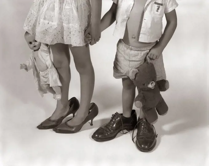1950S 1960S Close-Up Of Little Girl & Boy From Neck Down Wearing Parents' Shoes