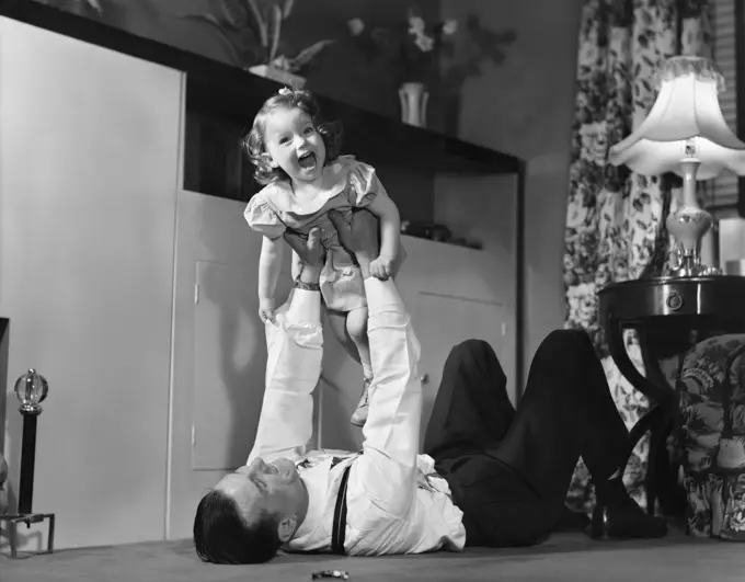 1950S Father Lying Floor Holding Daughter Girl Up In The Air 