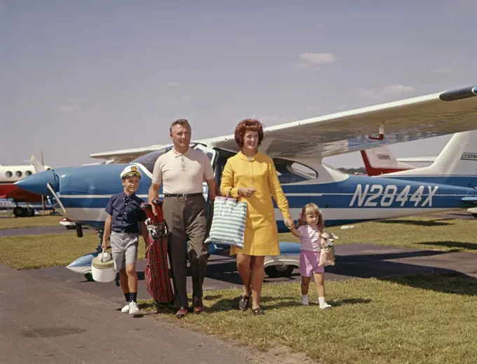 1960S Family Of 4 Walking From Private Plane Across Tarmac Travel Trip Luggage Mother Father Son Daughter