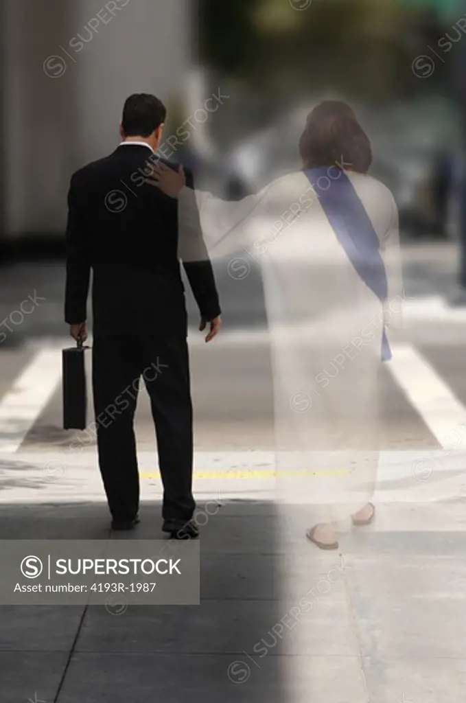 Double Exposure of a businessman walking down the street with Jesus at his side