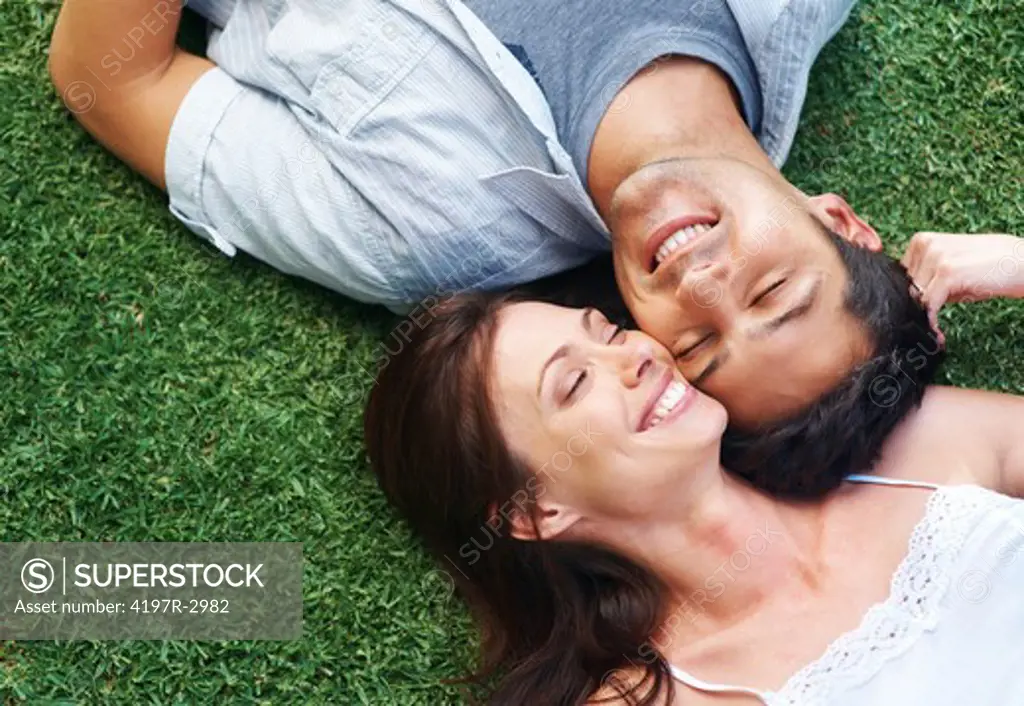 Portrarit of a happy young couple lying on grass in the park - Outdoor 
