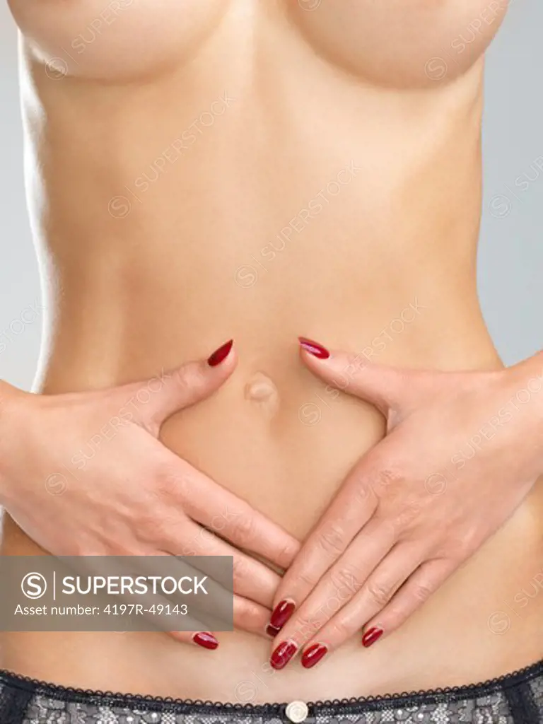Closeup image of a young womans hands over her flat bare stomach