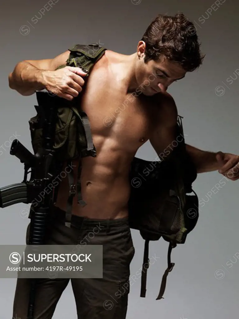 Attractive young soldier putting on  his bulletproof vest - isolated