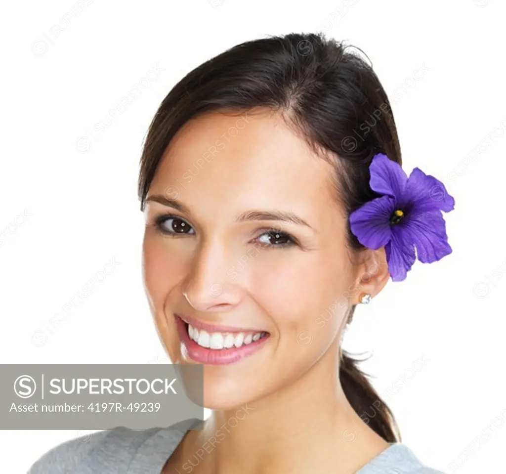 Closeup of a lovely brunette smiling at the camera with a purple hibiscus flower in her hair