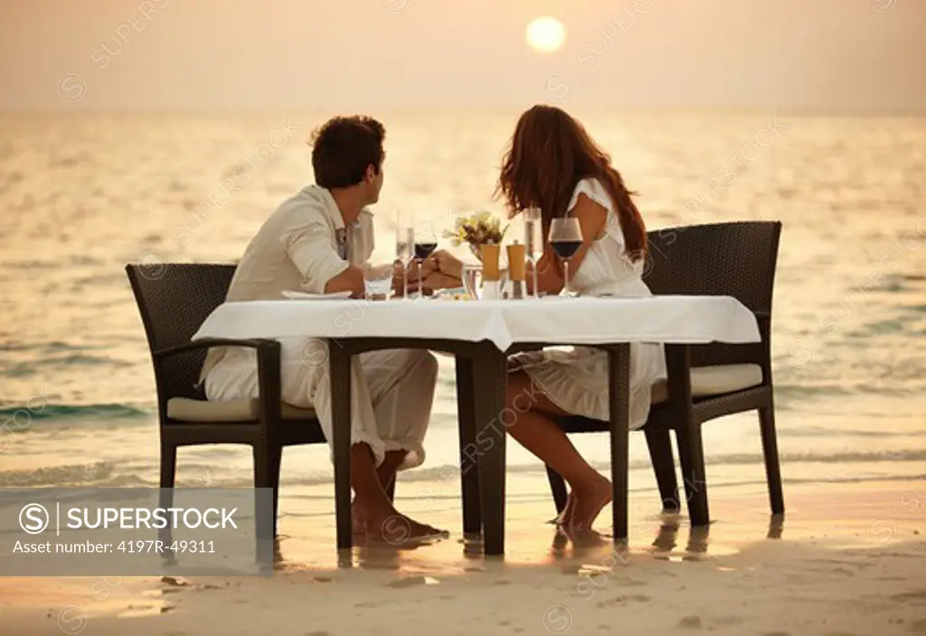 A young couple share a romantic dinner on the beach in the Maldives