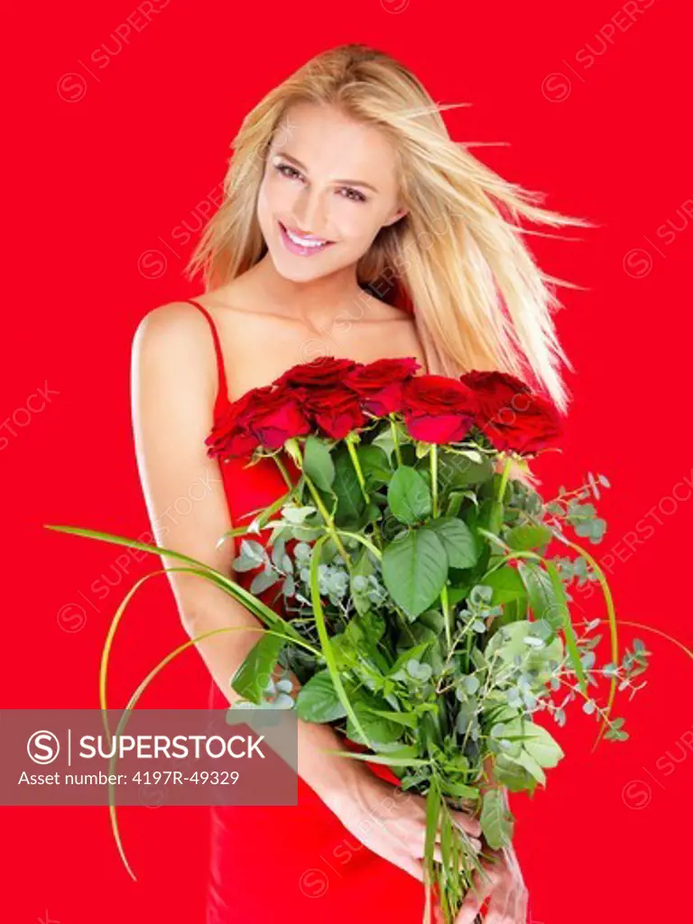 Attractive woman smiling while holding a bunch of red roses - isolated on red