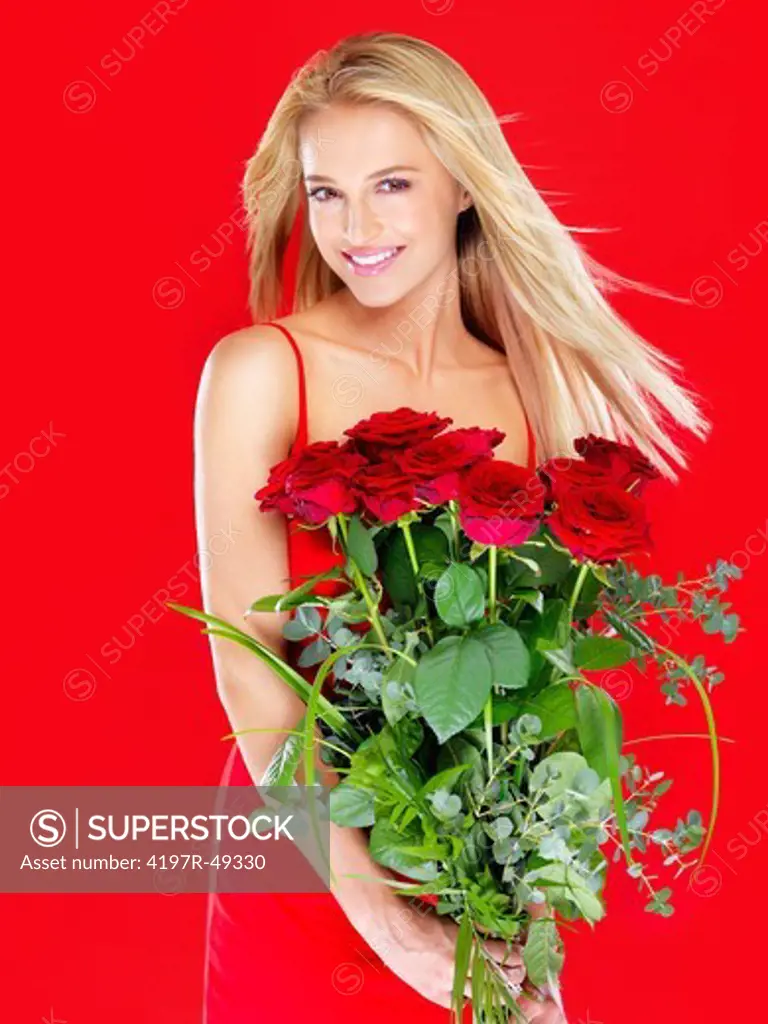 Lovely woman smiling while holding a bunch of red roses - isolated on red