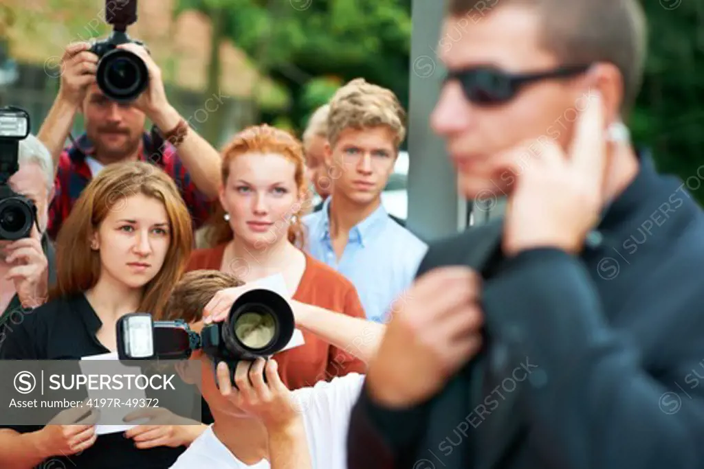 Fans and paparazzi looking at a security guard in anticipation of their favourite actress' arrival