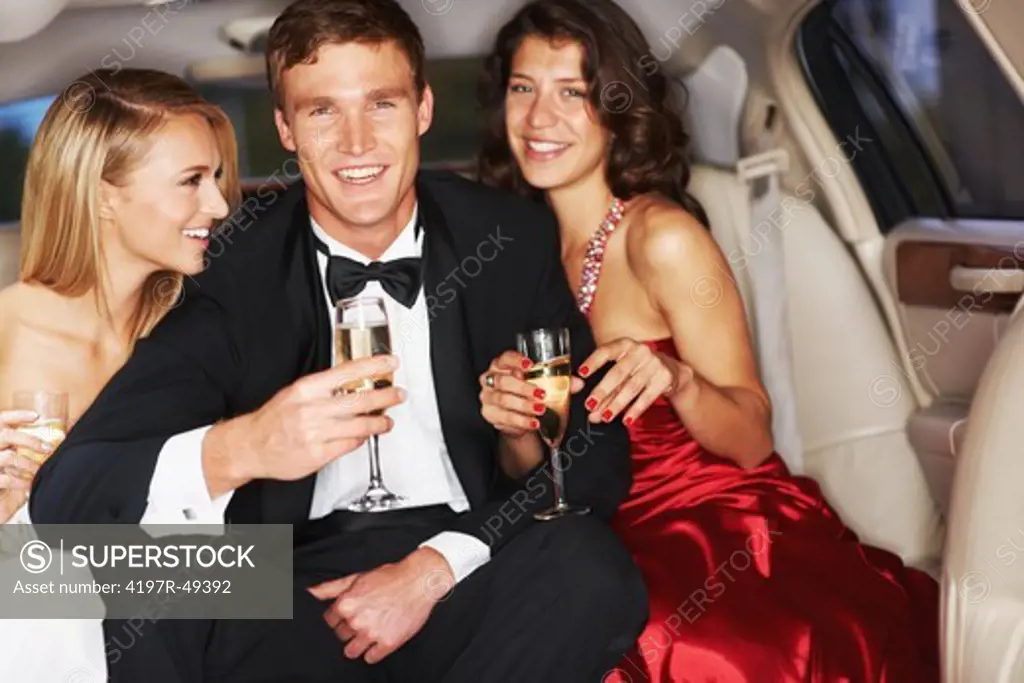 A handsome young celebrity drinking champagne flanked by two gorgeous woman in a limousine - Copyspace