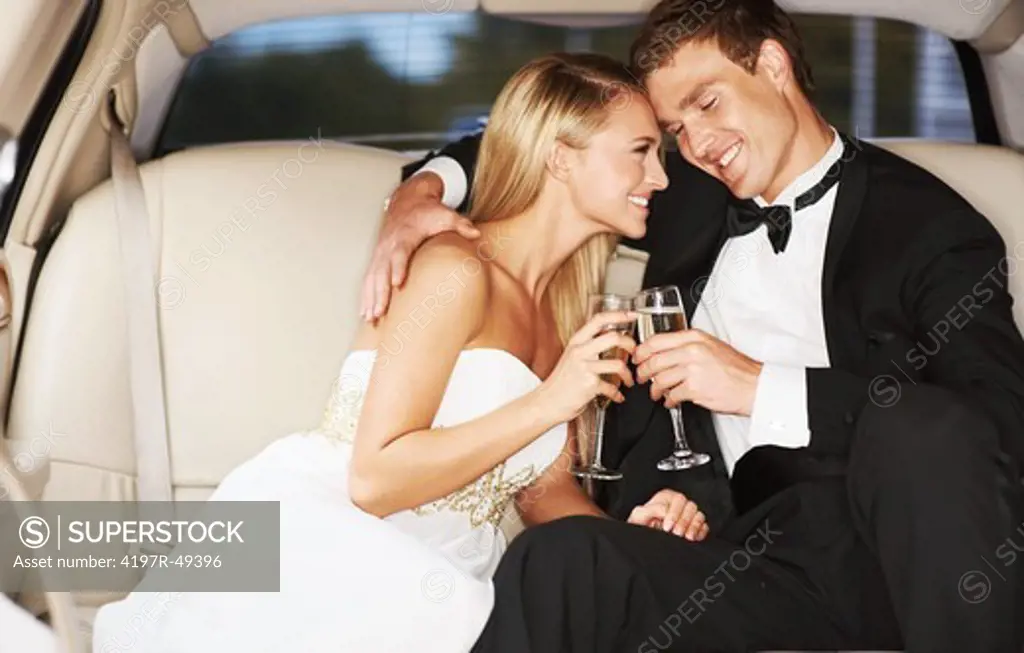 A young, blissfully happy couple enjoying champagne together in the back of a limousine