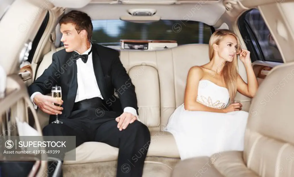 A young couple distance themselves from one another in the back of a limousine